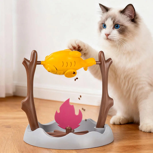 Jouet distributeur de friandises pour chat en forme de poisson, un chat ragdoll faisant tourner la broche de la patte