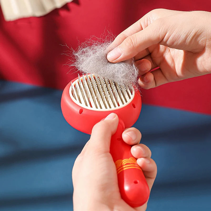 Main retirant le manchon de poils de la brosse à picots pour chat rouge