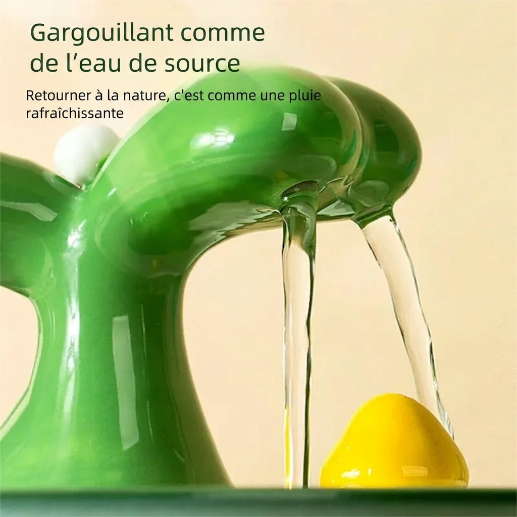 Gros plan des deux filets d'eau tombant du bec vert de la fontaine à eau chat céramique
