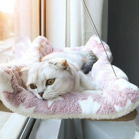 Chat gris allongé sur un hamac de fenêtre à housse peluche rose, devant une vitre ensoleillée — hamac de fenêtre pour chat