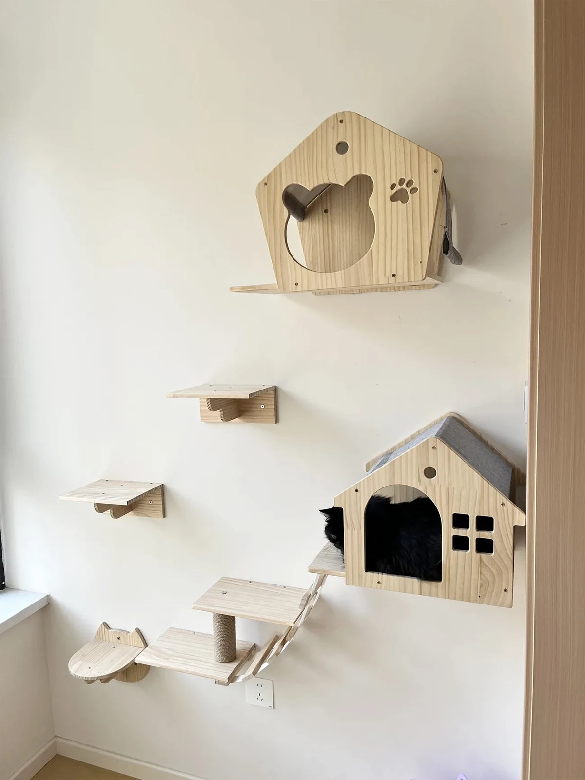 Maisonnettes murales en bois fixées au mur avec marches et passerelle, chat noir installé à — maisonnette murale pour chat